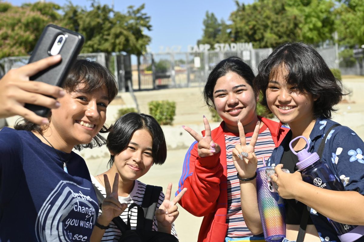 Senior Isabella Lopez-Escobar takes a selfie with 3 of the foreign exchange students visiting from Okinawa, outside the entrance of the K.R. Zack Earp District Stadium. 